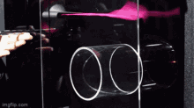 a person is holding a pink object in front of a glass door that says imgflip.com on the bottom right