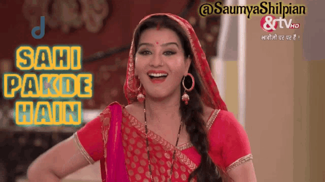 a woman in a red and gold outfit is smiling with the words sahi pakde hain behind her