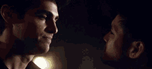 two men are looking into each other 's eyes in the dark .