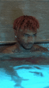 a man with red hair is swimming in a pool with blue water .