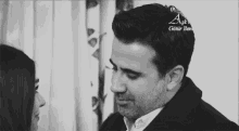 a black and white photo of a man and a woman looking into each other 's eyes .