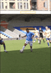 a man in a blue shirt is kicking a soccer ball in a stadium