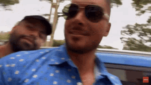 a man wearing sunglasses is standing next to another man