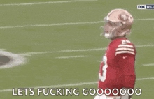 a football player wearing a red jersey and a helmet is standing on a football field .