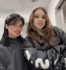 two girls are posing for a picture with one wearing a jacket with the number 2 on the sleeve