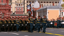 a group of soldiers marching in front of a building with a flag that says ' russia ' on it