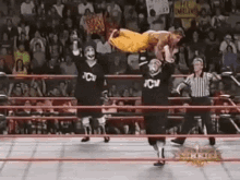 a wrestler is being lifted in the air by another wrestler during a match in a wrestling ring .