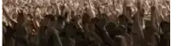 a large group of people are standing in a crowd and raising their hands in the air .
