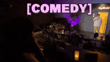a man stands in front of a microphone with the word comedy above him