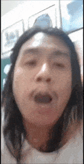 a man with long hair is making a funny face with his mouth open .