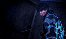 a man in a blue and black camouflage jacket is holding a sword