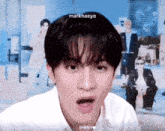 a young man with a surprised look on his face is wearing a white shirt and has the name markhaeyo on his head .