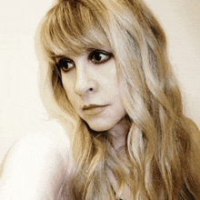 a close up of a woman 's face with long blonde hair and bangs