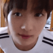 a close up of a person 's face with a white shirt and black stripes on it .