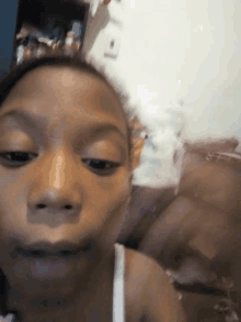 a close up of a young girl 's face with a white shirt on