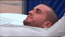 a man with a beard is laying in a hospital bed looking up .