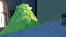 a green stuffed animal is sitting on a table in a room