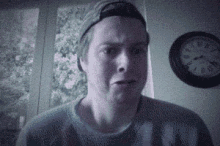 a man wearing a hat and a sweater is making a funny face .