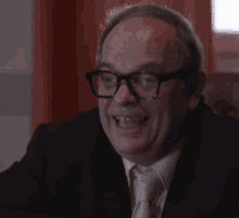 a man in a suit and tie with glasses looks at the camera