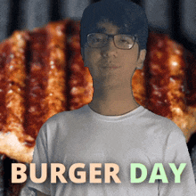 a man wearing glasses is standing in front of a hamburger that says burger day on it