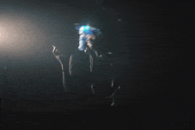 a woman in a dark room is holding a blue object in her hand