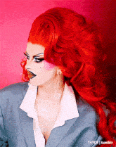 a woman with red hair is wearing a gray suit