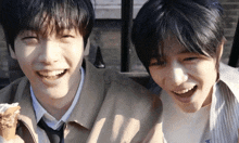 two young men are smiling and eating ice cream