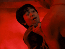 a man is holding a young boy 's neck in a dark room