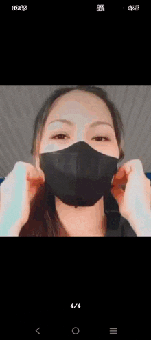 a woman wearing a black face mask is taking a picture of herself .