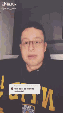 a man wearing glasses and a black hoodie is making a funny face and giving a thumbs up .