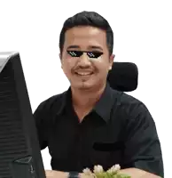 a man wearing sunglasses and a black shirt sits in front of a computer monitor