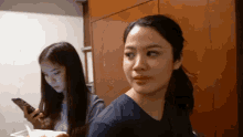 a woman looking at her phone while another woman looks at her