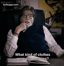 a man wearing glasses and a vest is sitting at a desk and asking what kind of clothes are you wearing .