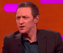 a man in a suit is making a funny face on a red background