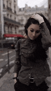 a woman in a green jacket is walking down a street