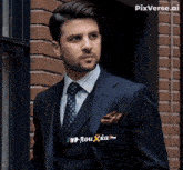 a man wearing a suit and tie with rou ka written on his pocket square