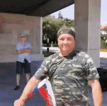 a man in a camouflage shirt stands in front of a building