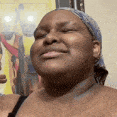 a woman wearing a head scarf is smiling in front of a painting