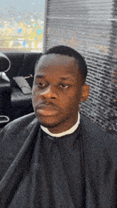 a man in a black cape is sitting in a barber chair