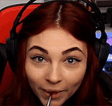 a close up of a woman wearing headphones and holding a straw in her mouth