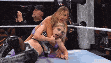 two women wrestling in a ring with a w logo on the wall