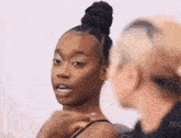 a woman with a bun on her head is talking to another woman while another woman looks on .