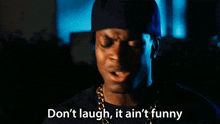 a man says " don 't laugh it ain 't funny " in front of a dark background