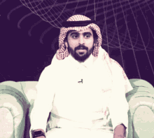 a man with a beard wearing a head scarf and a white shirt with the letter t on it