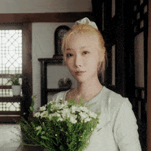 a woman holding a bouquet of white flowers in a room