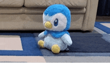 a stuffed penguin is sitting on a blue rug