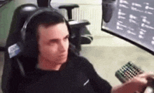 a man wearing headphones is sitting in a chair in front of a computer screen .
