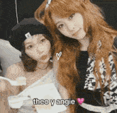 two girls are posing for a picture together and one of them is holding a piece of food .