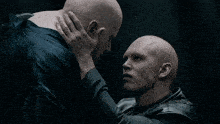 two bald men are dancing in a dark room with their hands in the air