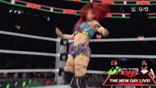 a woman is dancing in a wrestling ring with a sign that says the new day live